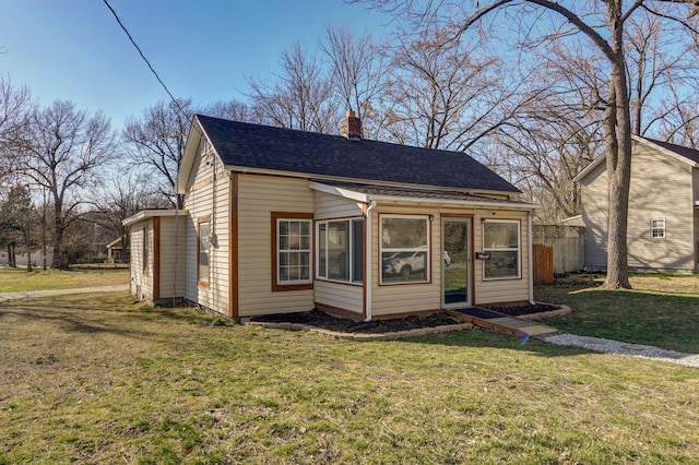 bungalow-style house featuring a shingled roof, a front lawn, fence, and a chimney