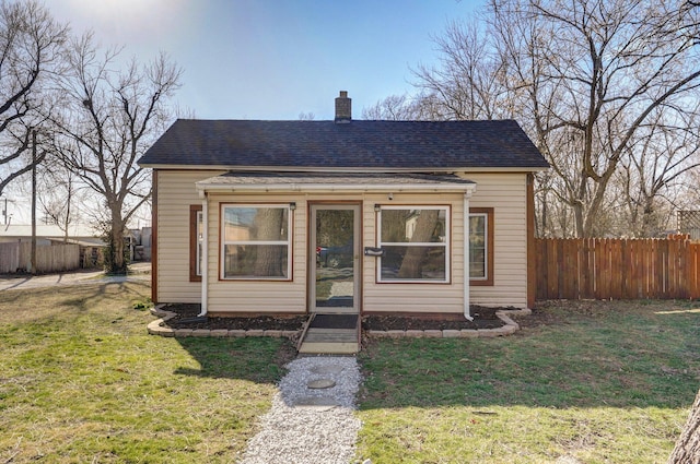 bungalow-style home featuring a shingled roof, a chimney, a front lawn, and fence