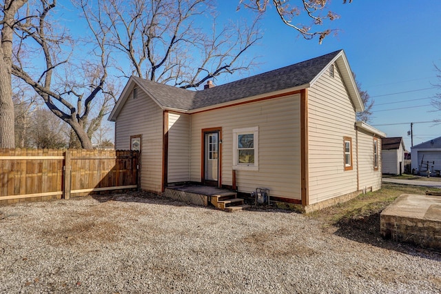 back of property with fence and a shingled roof