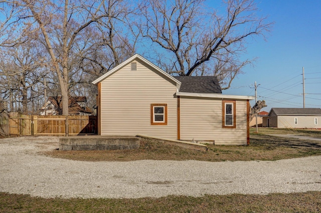 view of home's exterior featuring roof with shingles and fence