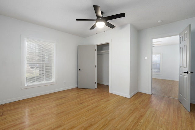 unfurnished bedroom featuring a closet, light wood-style flooring, a ceiling fan, and baseboards