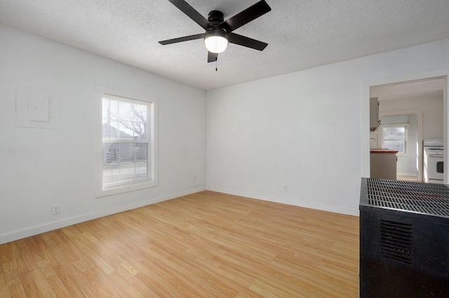 empty room featuring baseboards, plenty of natural light, a textured ceiling, and wood finished floors