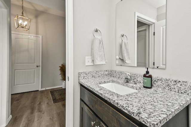 bathroom with vanity, an inviting chandelier, wood finished floors, and baseboards