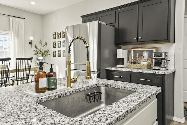 kitchen featuring tasteful backsplash, recessed lighting, dark cabinetry, and freestanding refrigerator