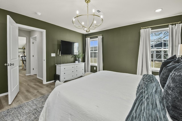 bedroom featuring a notable chandelier, multiple windows, visible vents, and wood finished floors