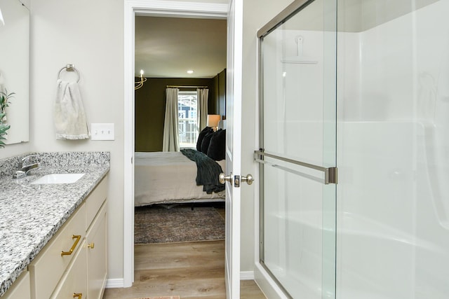 ensuite bathroom with a stall shower, vanity, ensuite bathroom, and wood finished floors