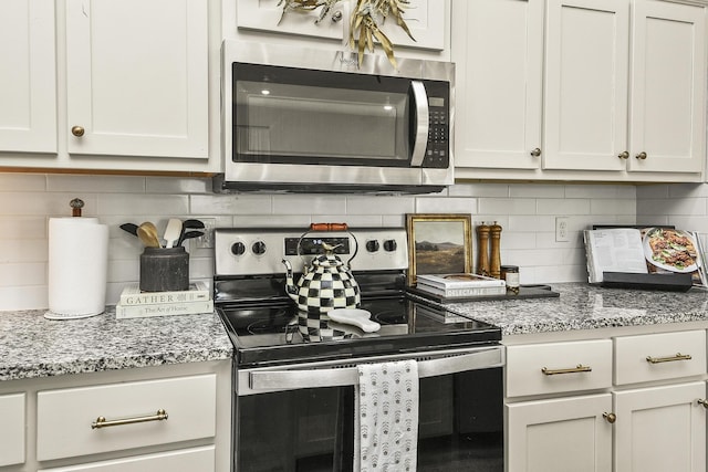 kitchen with backsplash, white cabinets, stainless steel appliances, and light stone countertops