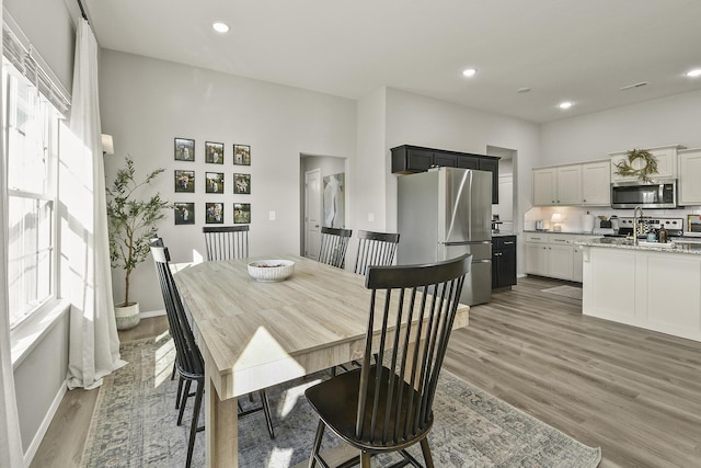 dining room with light wood-style flooring, recessed lighting, and baseboards