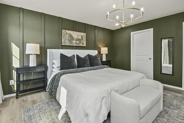 bedroom with baseboards, light wood finished floors, and a chandelier