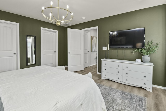 bedroom with a chandelier, baseboards, and wood finished floors