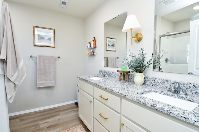 full bath featuring a shower stall, wood finished floors, visible vents, and a sink