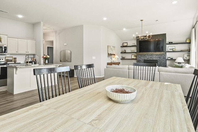 dining area with wood finished floors, recessed lighting, a fireplace, and vaulted ceiling