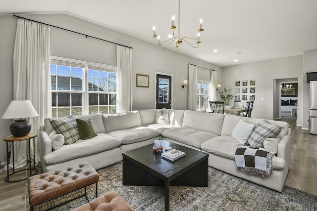 living area with lofted ceiling, an inviting chandelier, and wood finished floors