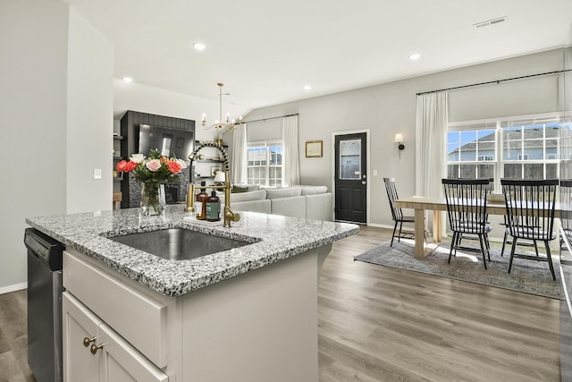 kitchen with visible vents, light stone countertops, dishwasher, an inviting chandelier, and light wood-style floors