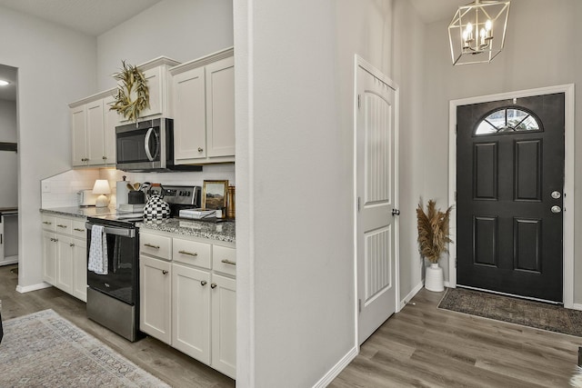 entryway featuring a chandelier, baseboards, and wood finished floors