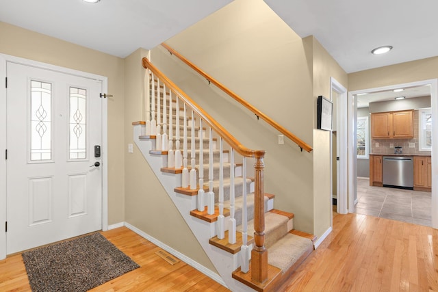 entryway with visible vents, baseboards, stairway, and light wood finished floors