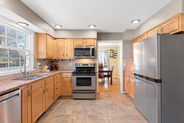 kitchen featuring backsplash, light brown cabinetry, light tile patterned flooring, stainless steel appliances, and a sink