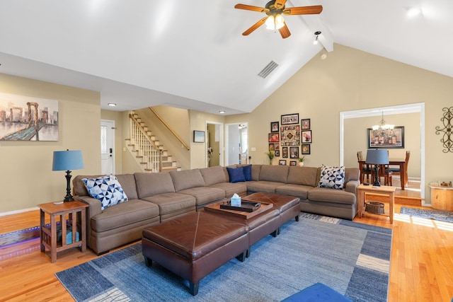 living room with visible vents, beamed ceiling, stairs, wood finished floors, and high vaulted ceiling