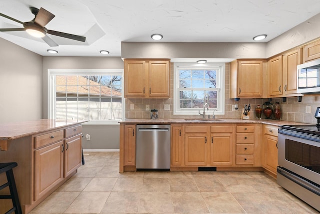 kitchen featuring a sink, tasteful backsplash, appliances with stainless steel finishes, and light brown cabinets