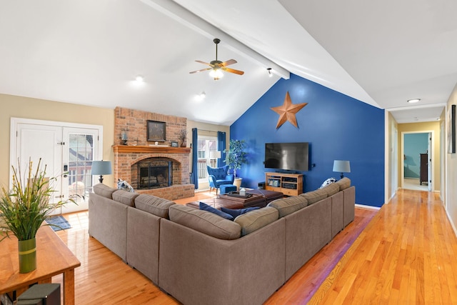 living room featuring vaulted ceiling with beams, a fireplace, light wood-type flooring, and ceiling fan