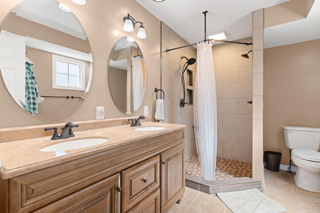 bathroom featuring tile patterned flooring, tiled shower, toilet, and a sink