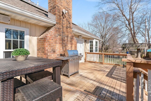 wooden terrace featuring a grill and outdoor dining space