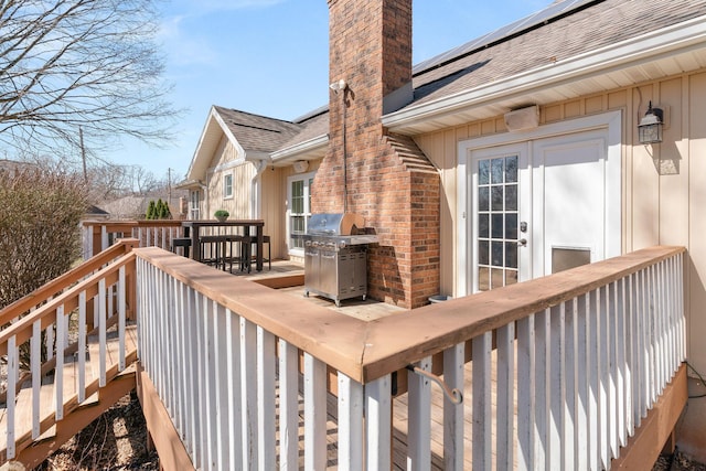 wooden deck with french doors, outdoor dining area, and a grill