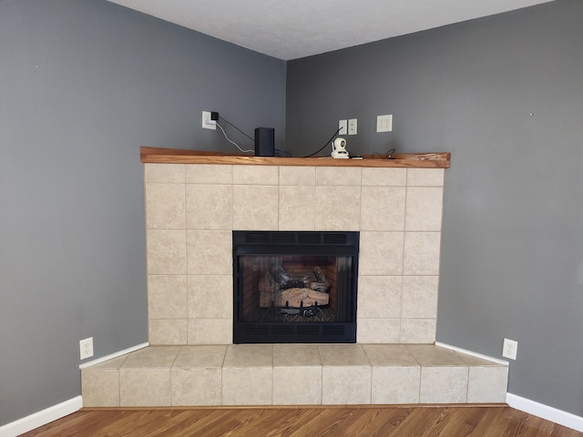 interior details with baseboards, a fireplace with raised hearth, and wood finished floors