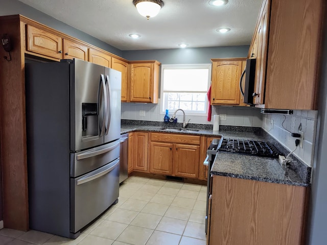 kitchen featuring a sink, tasteful backsplash, appliances with stainless steel finishes, brown cabinetry, and light tile patterned floors