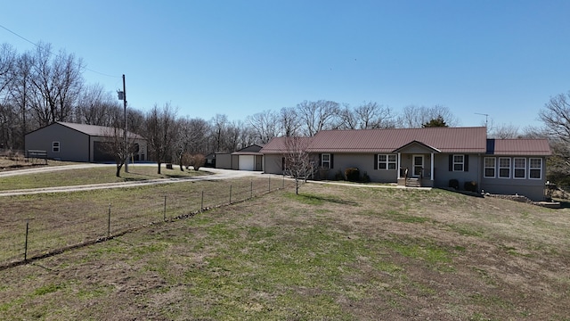 ranch-style house featuring a front lawn, fence, metal roof, a garage, and driveway