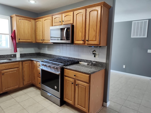 kitchen featuring tasteful backsplash, visible vents, baseboards, appliances with stainless steel finishes, and a sink