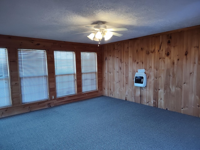 spare room featuring ceiling fan, wooden walls, carpet floors, and a textured ceiling