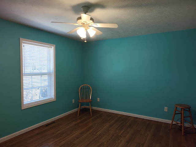 unfurnished room featuring dark wood-style floors, visible vents, a ceiling fan, and baseboards