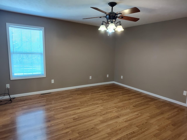 spare room featuring visible vents, wood finished floors, baseboards, and ceiling fan