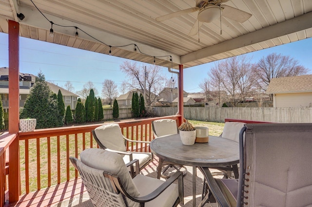 wooden terrace featuring a yard, a ceiling fan, outdoor dining area, and a fenced backyard