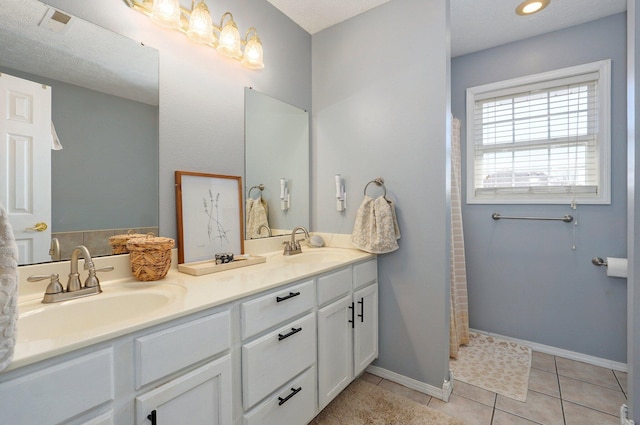 full bath with tile patterned flooring, double vanity, baseboards, and a sink