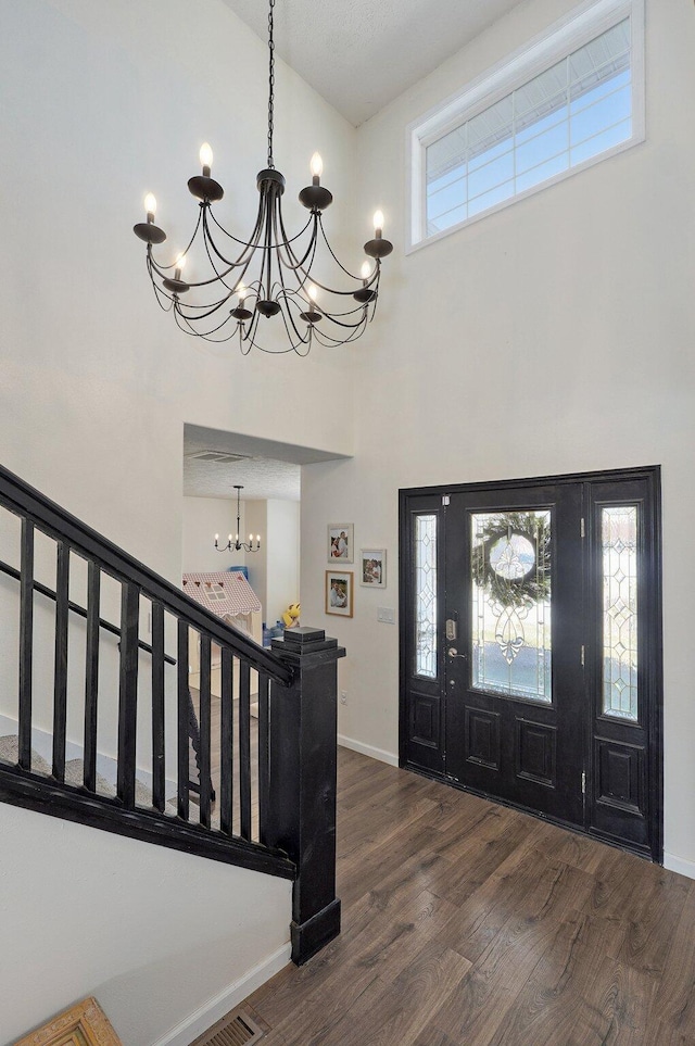 foyer featuring baseboards, a high ceiling, stairs, dark wood-type flooring, and a notable chandelier