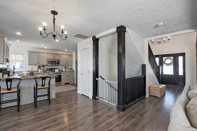 kitchen featuring visible vents, gray cabinetry, dark wood-style floors, stainless steel appliances, and a chandelier