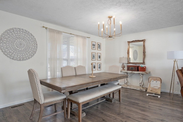 dining space with a textured ceiling, wood finished floors, visible vents, and a chandelier