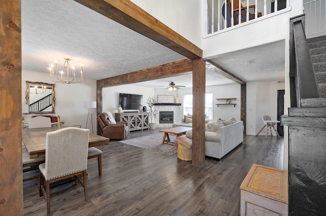 living area featuring beamed ceiling, dark wood-type flooring, a textured ceiling, stairway, and a fireplace