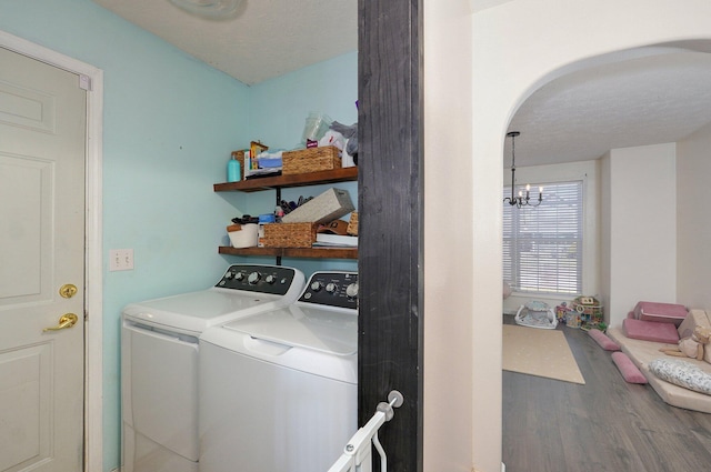 laundry room with wood finished floors, washing machine and dryer, arched walkways, an inviting chandelier, and laundry area