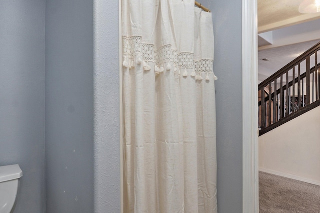 full bath featuring a shower with shower curtain, toilet, and baseboards