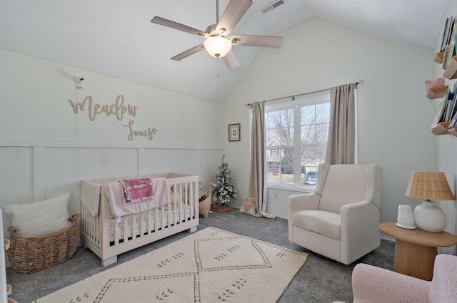 carpeted bedroom with visible vents, lofted ceiling, a nursery area, a decorative wall, and a ceiling fan