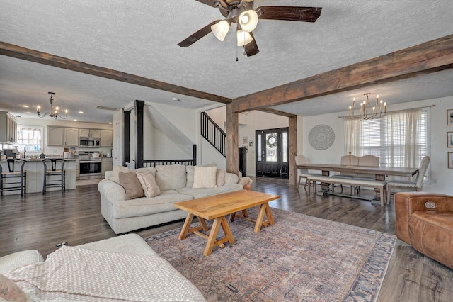 living area featuring dark wood-style floors, beamed ceiling, ceiling fan with notable chandelier, and a textured ceiling