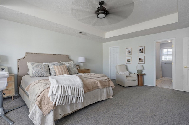 bedroom featuring visible vents, ceiling fan, carpet floors, a textured ceiling, and a raised ceiling