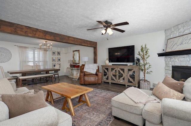 living room featuring a fireplace, ceiling fan with notable chandelier, wood finished floors, and a textured ceiling