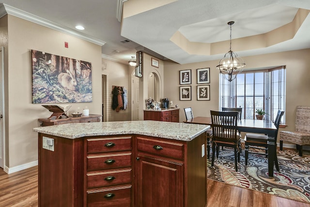 kitchen with ornamental molding, decorative light fixtures, wood finished floors, reddish brown cabinets, and a chandelier