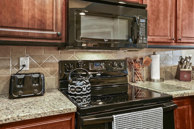 kitchen featuring light stone counters, backsplash, and black appliances