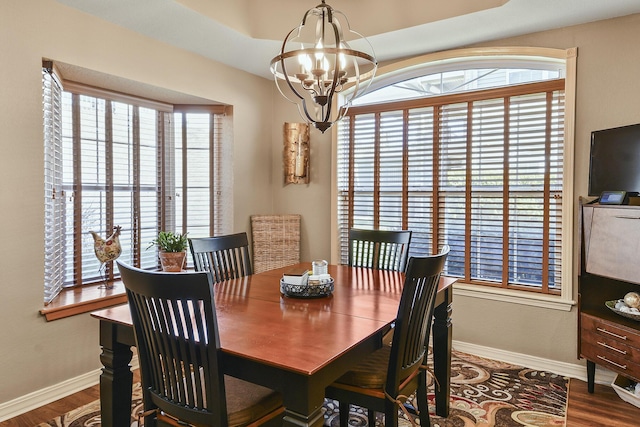 dining space featuring baseboards, an inviting chandelier, and wood finished floors