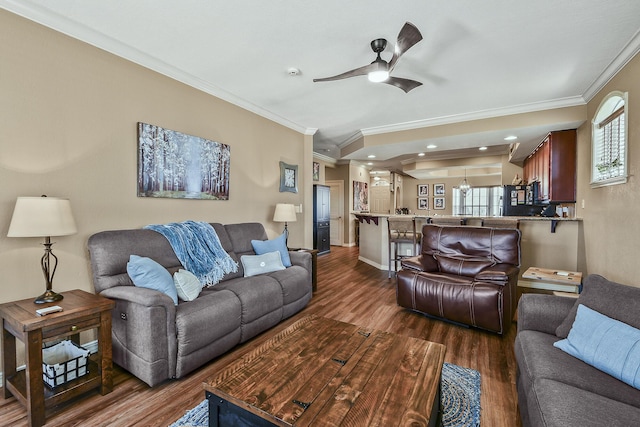 living area with dark wood finished floors, ceiling fan, baseboards, and ornamental molding